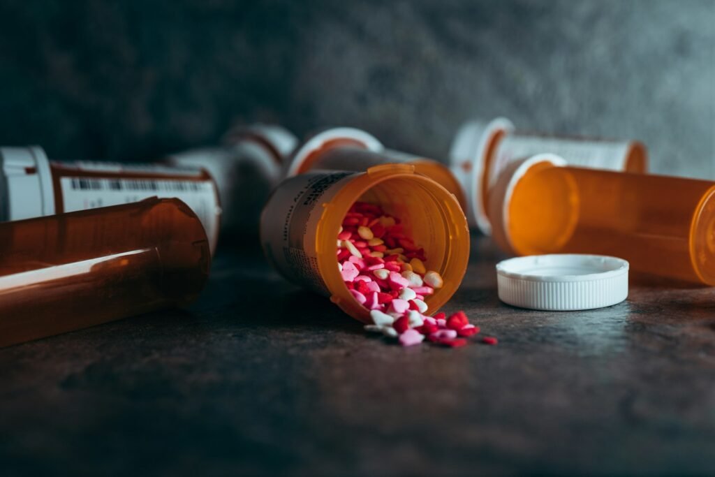 Orange prescription pill bottles tipped over on a dark countertop, with pills spilling out